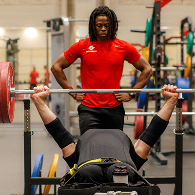 Para-athlete performing a flat bench press with their spotter.