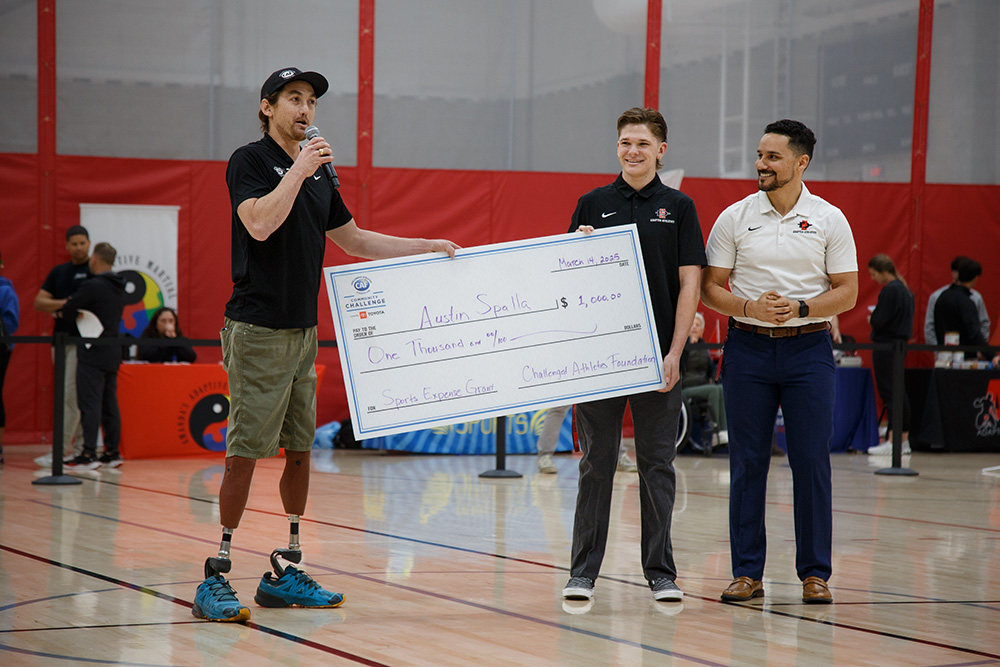 An oversized check for $1000 is awarded to Austin Spalla by the Challenged Athletes Foundation.