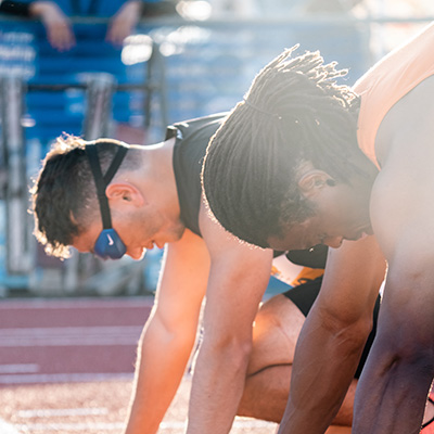 A blind athlete and his guide are in the ready position for a race.