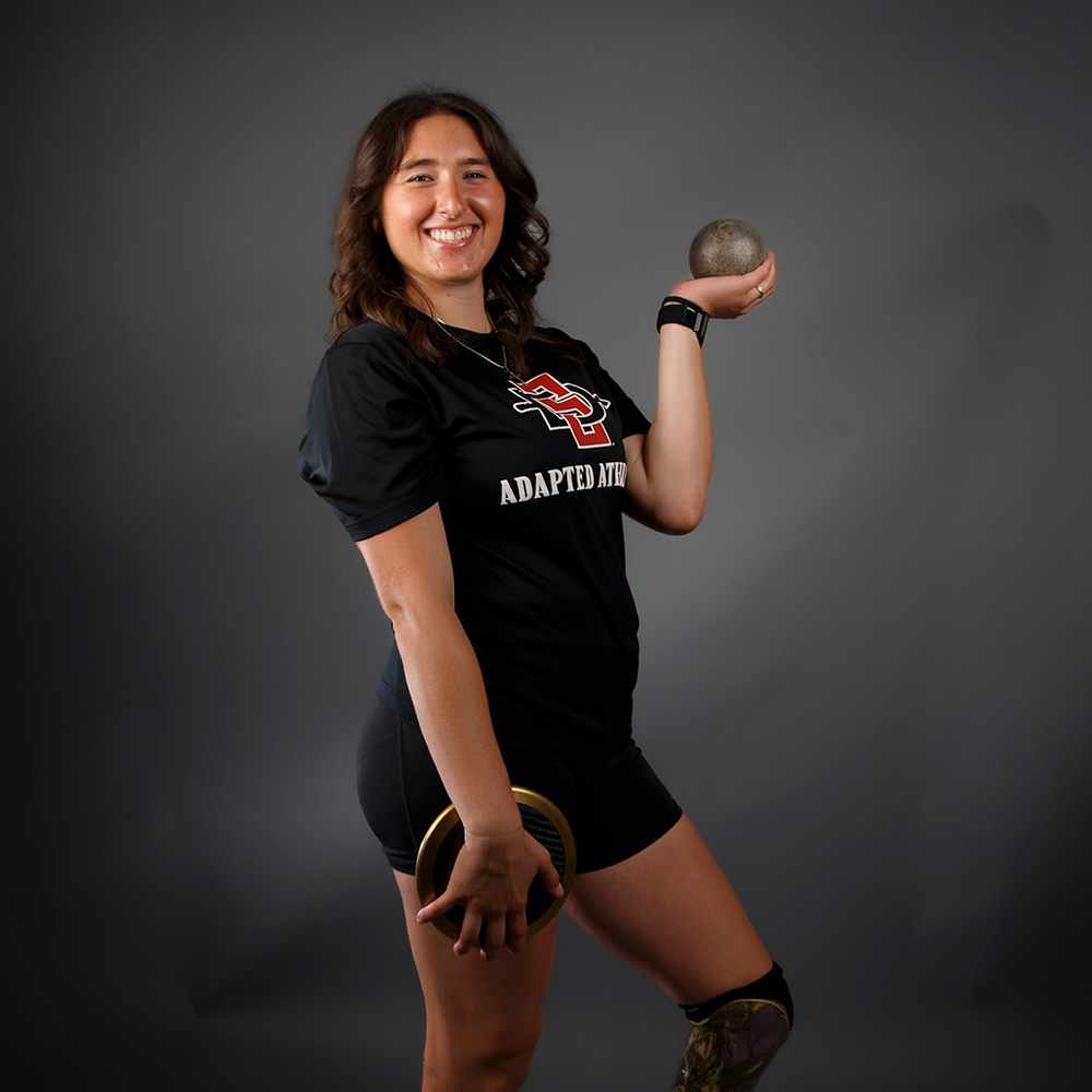 Chloe Chavez posing with a shot and discus.