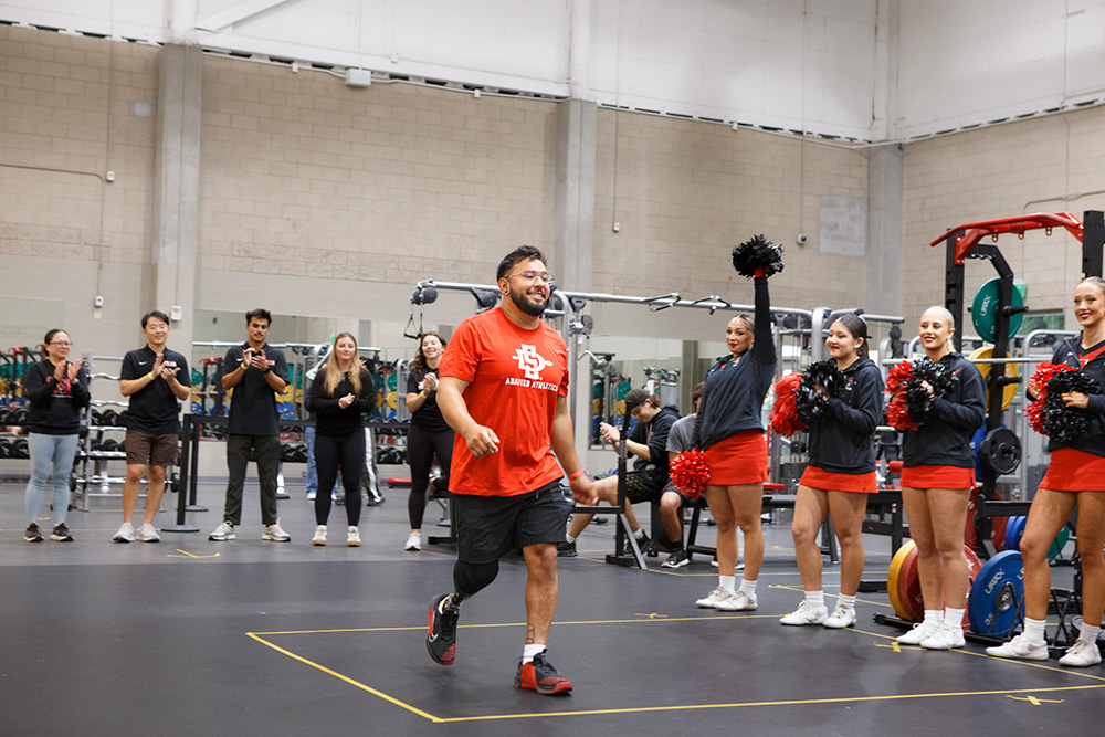 An athlete prepares to begin lifting while onlookers cheer him on.