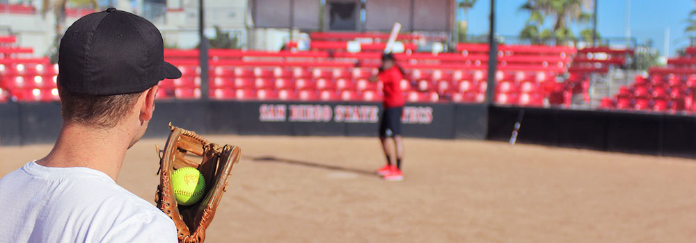 Softball: players pitcher with ball looking at hitter at base