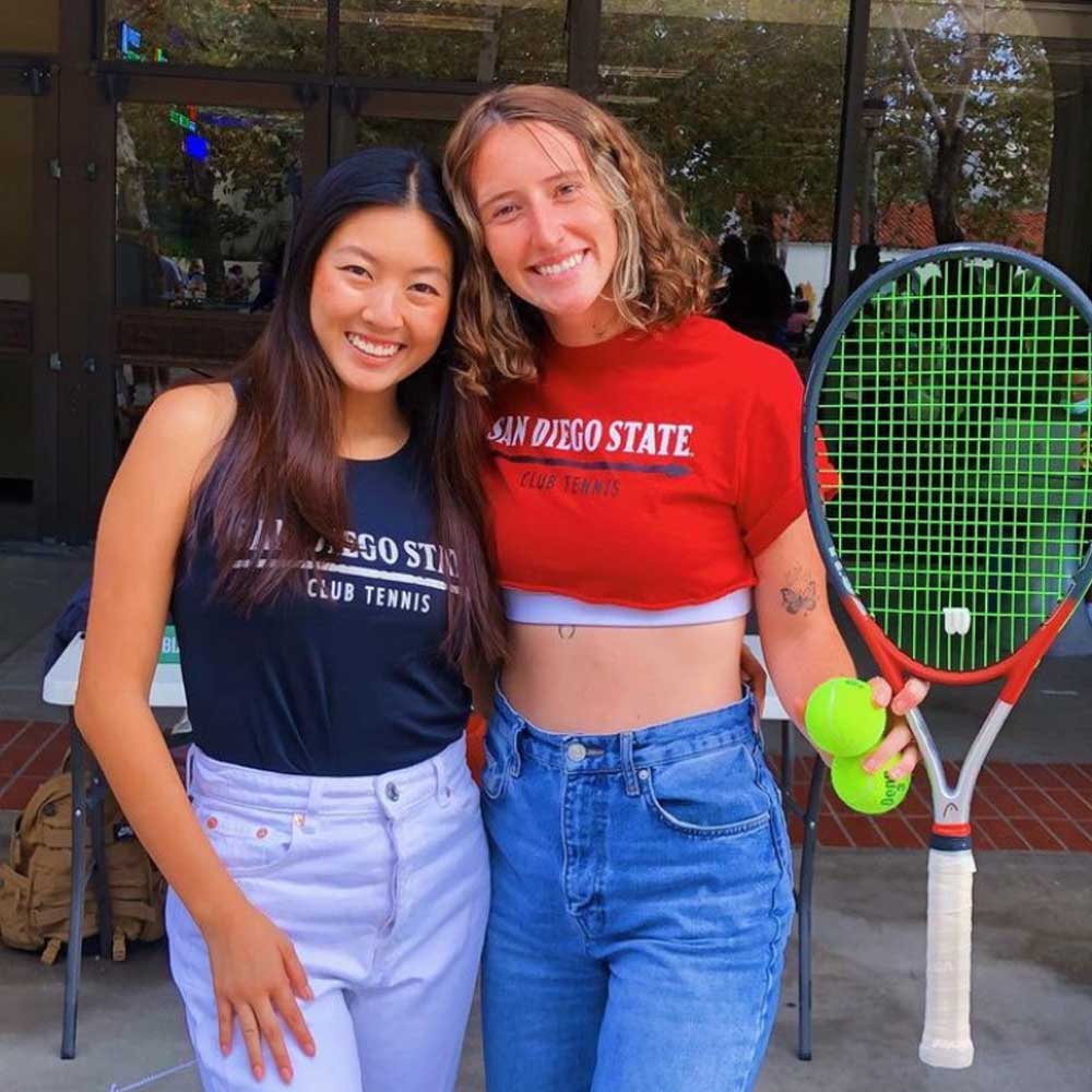 Two smiling tennis club members at a recruiting event