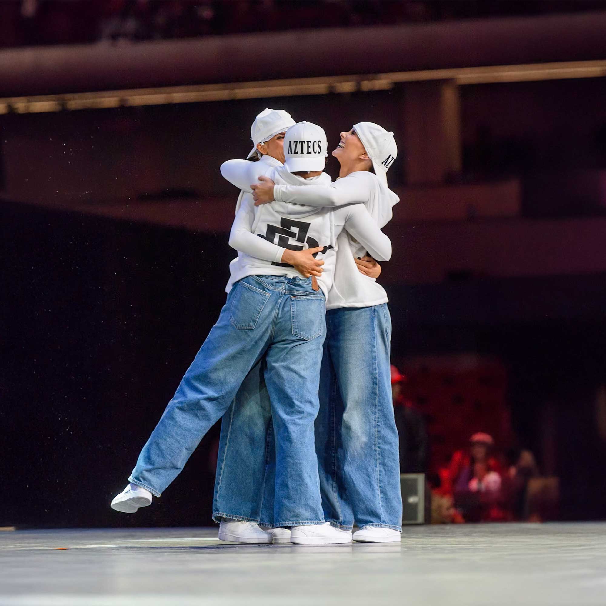 Three Dance Team members hugging on stage after a performance