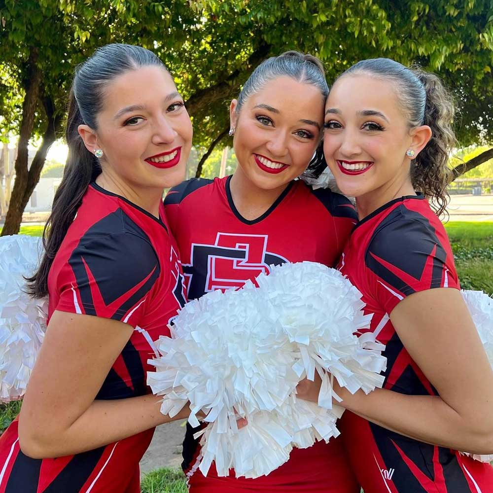 Three smiling Dance Team members holding pom-poms