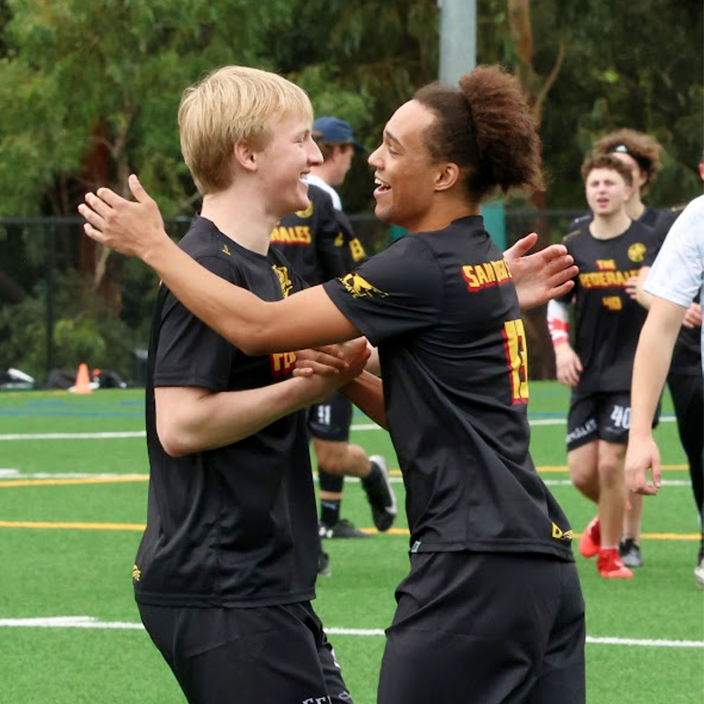 Two players patting each other on the back after a game on the field