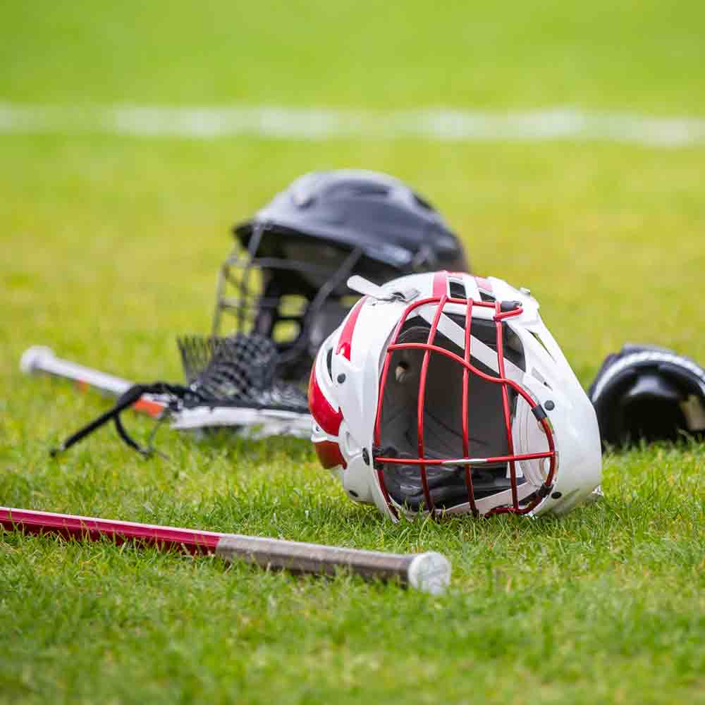 Lacrosse sticks, helmets, and balls on green grass field.