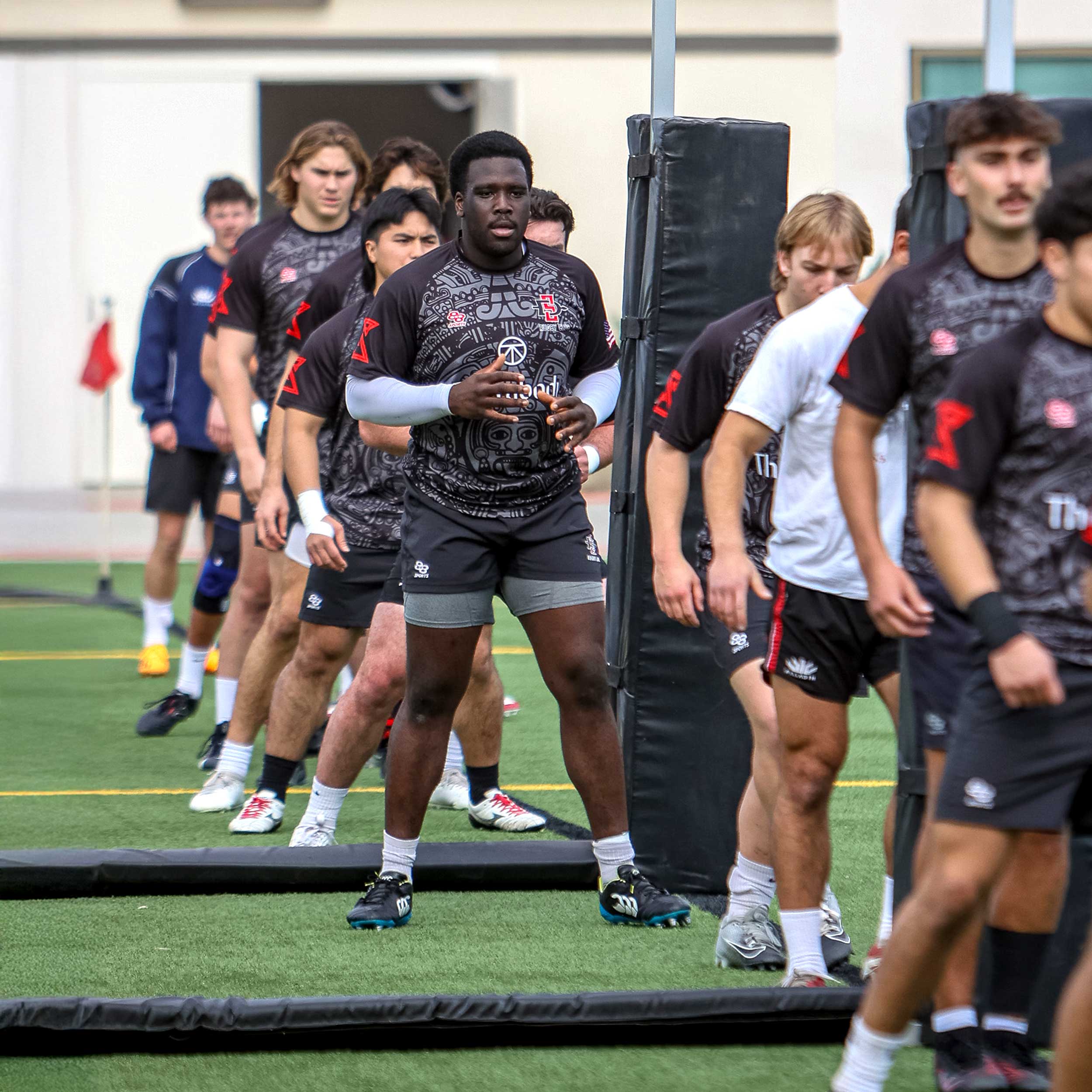 Row of Men's Rugby Club members training on the grass field
