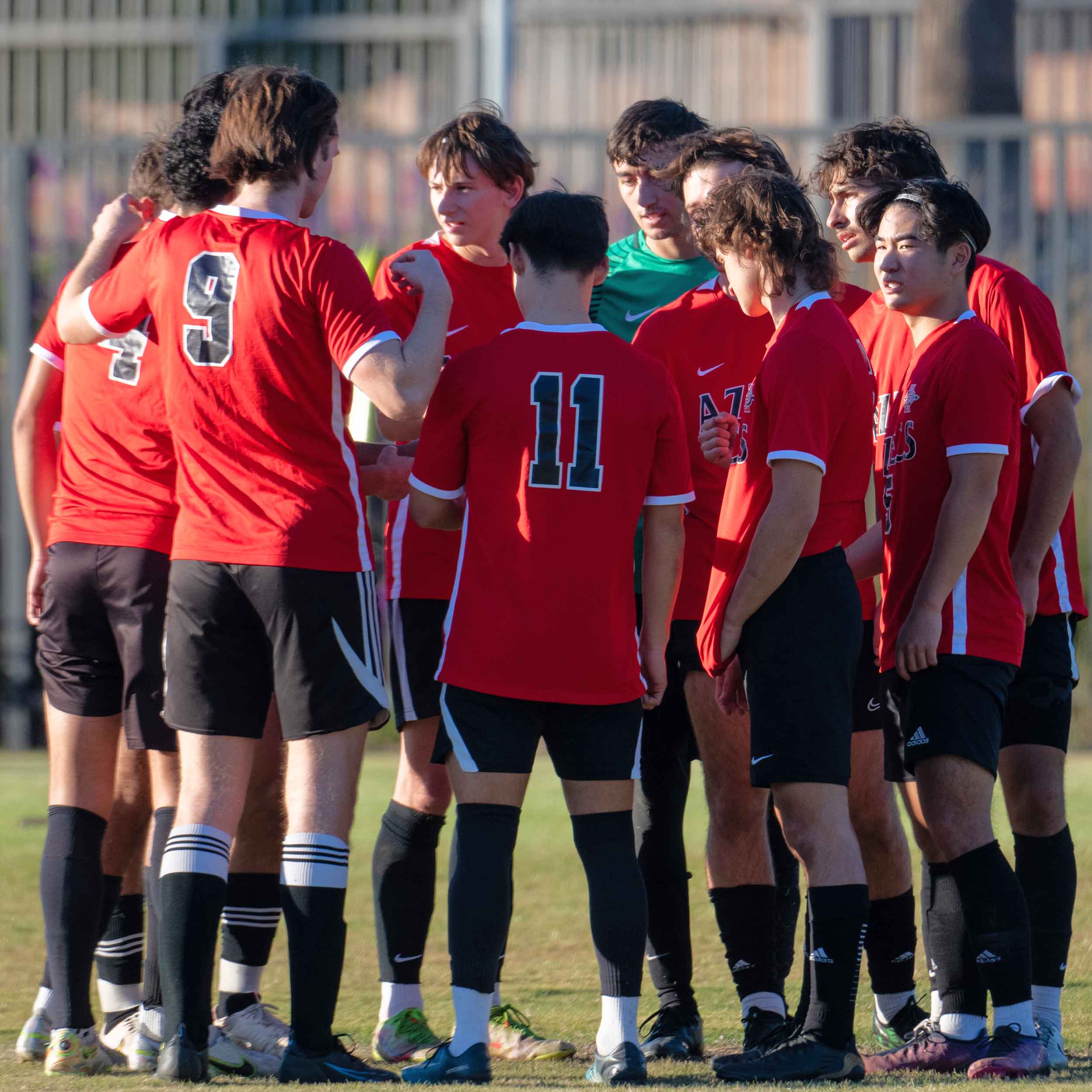 Men's Soccer Club members in a huddle on the field