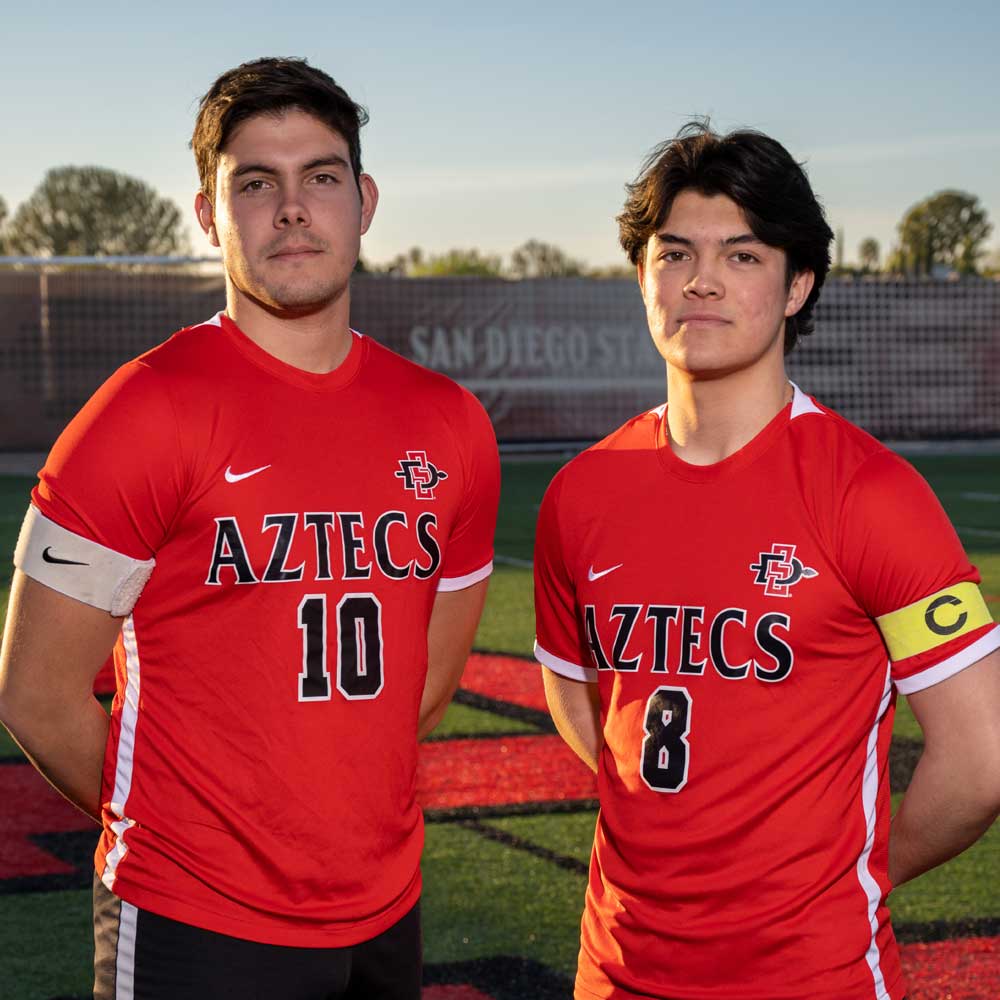 Two men's soccer club members posing in red jerseys 