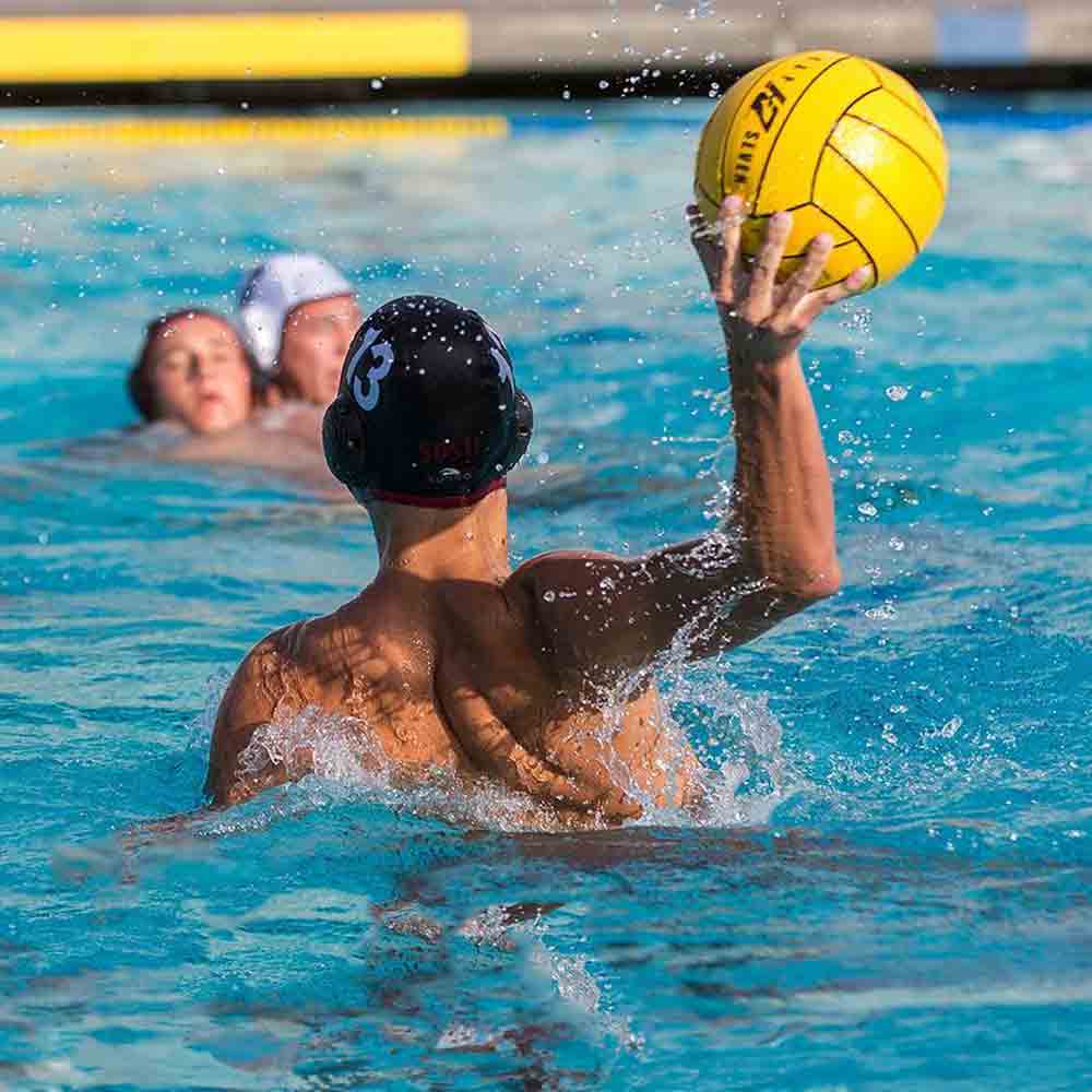 SDSU Men's Water Polo player preparing to throw the ball in a competitive match.