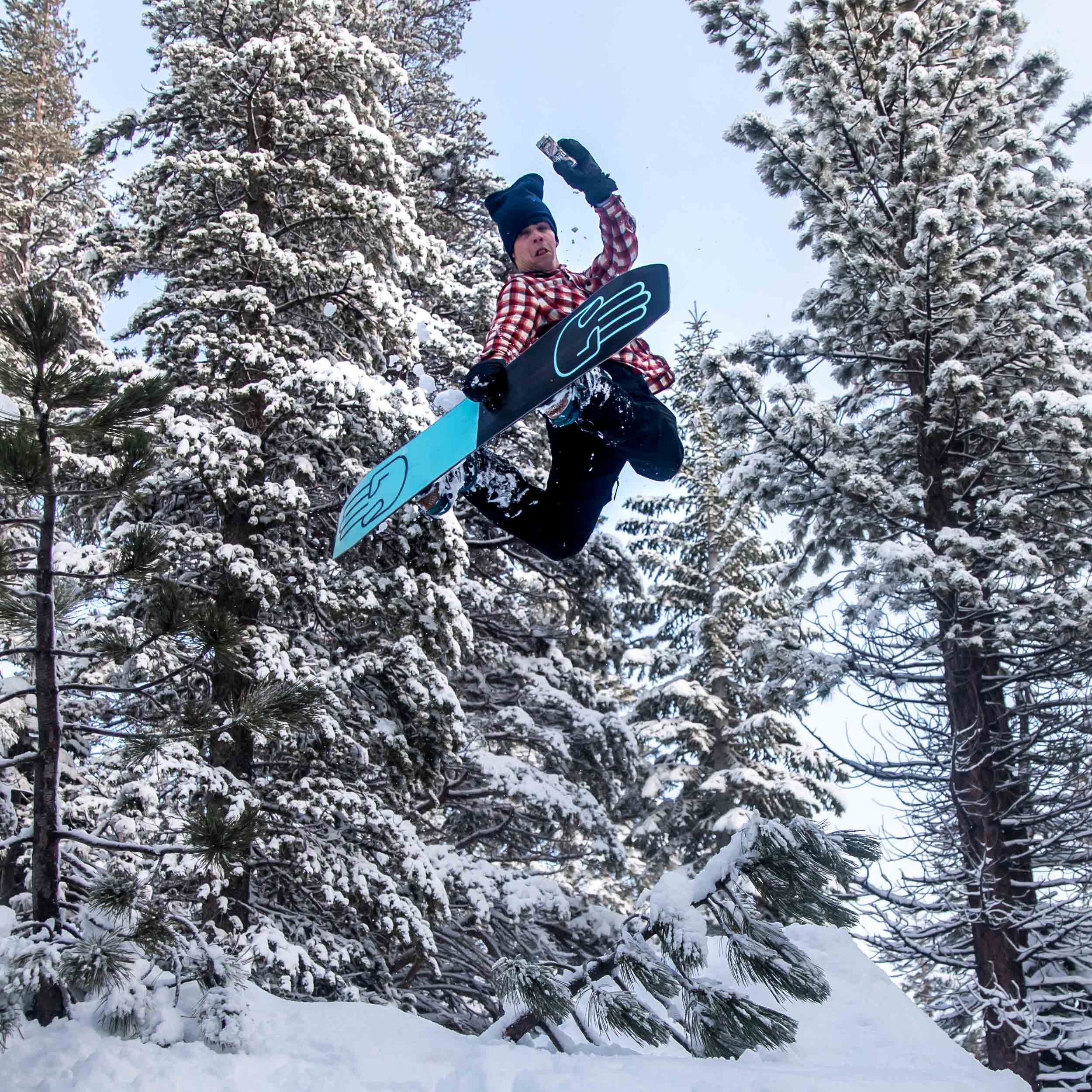 Snowboarder making a jump against snowy trees