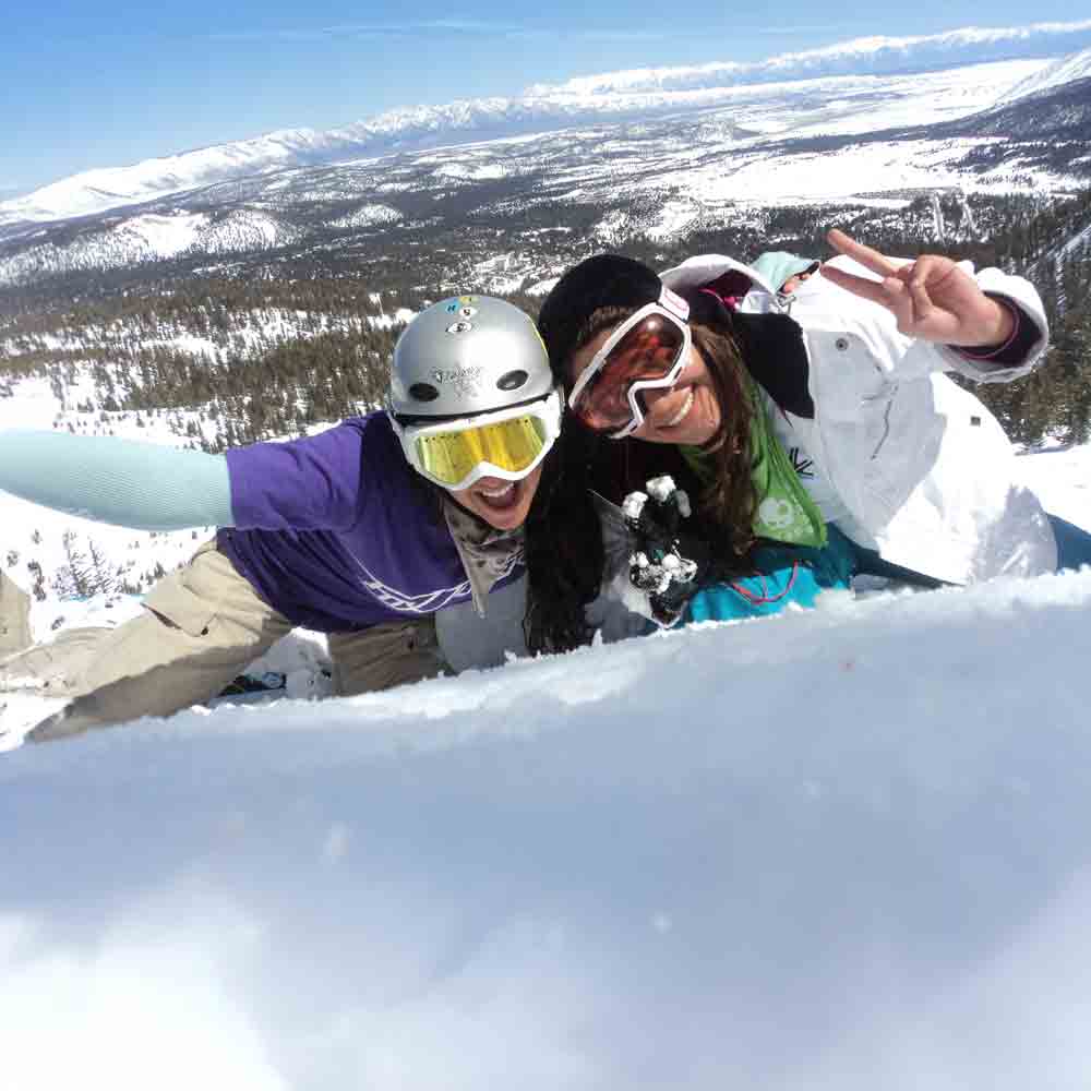 Two snowboarders smiling for a photo in the snow.