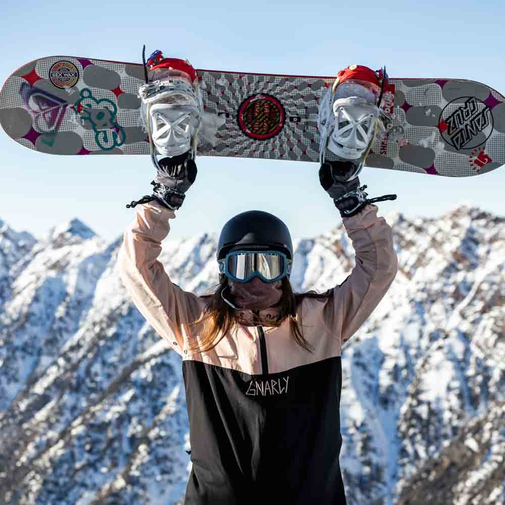 A snowboarder holding up their snowboard over their head