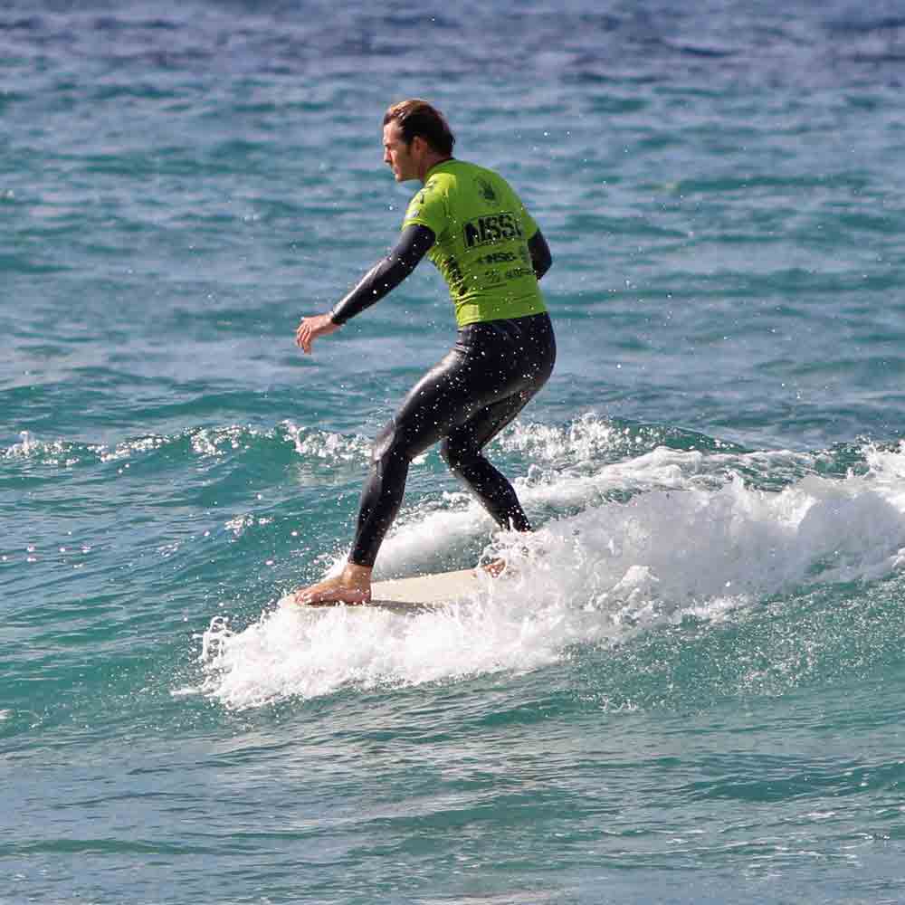 Surfer standing on his surfboard while riding a small wave