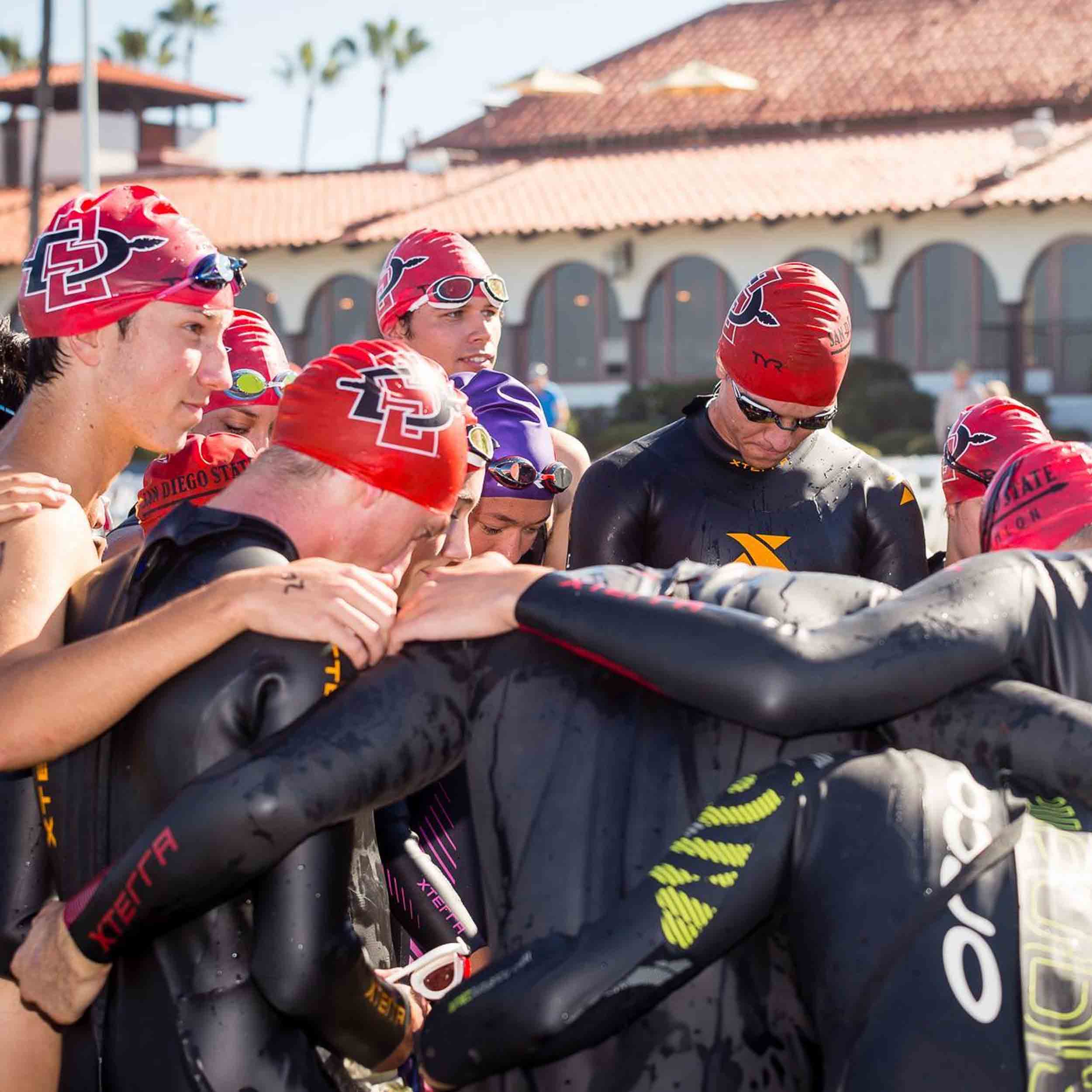 Triathlon members in wetsuits in a group huddle