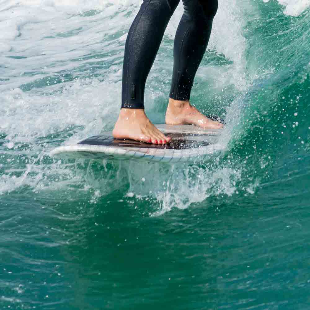 Close up of wakeboarder's board and legs on the water