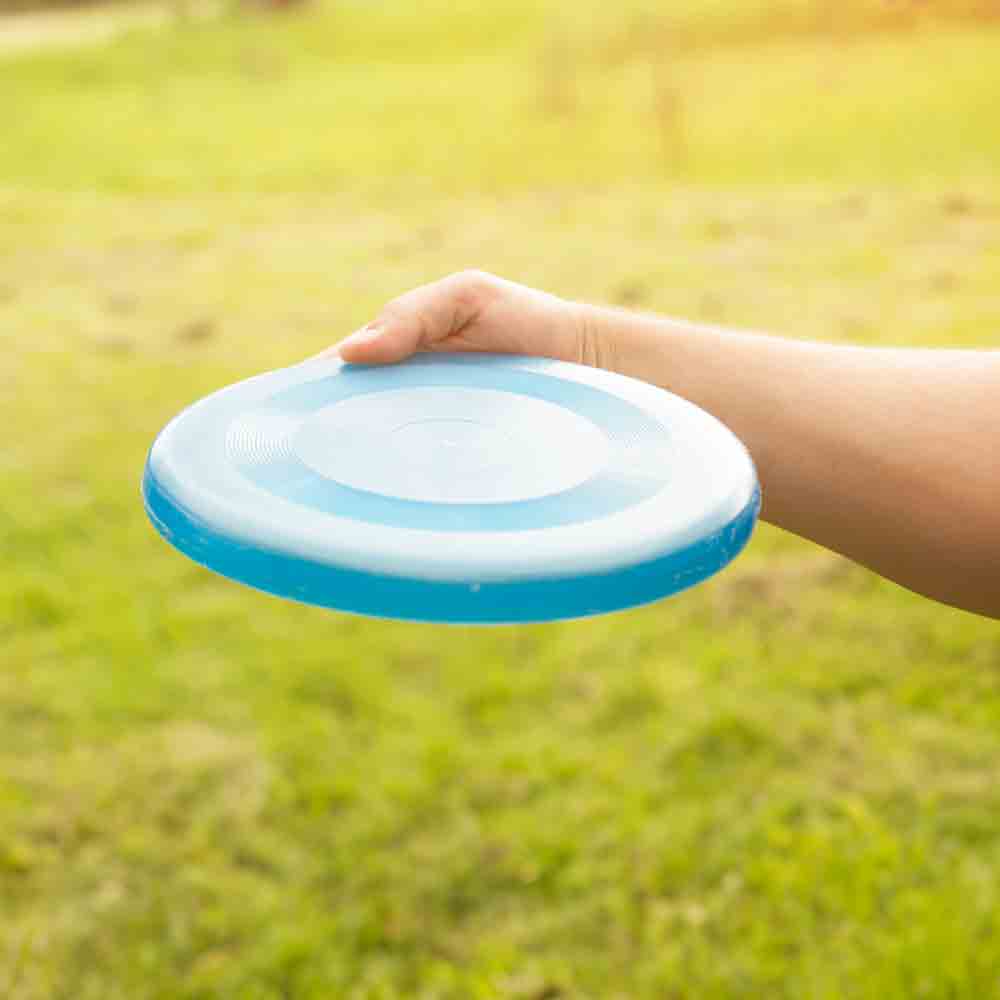 Arm holding a blue frisbee disk against a grass background