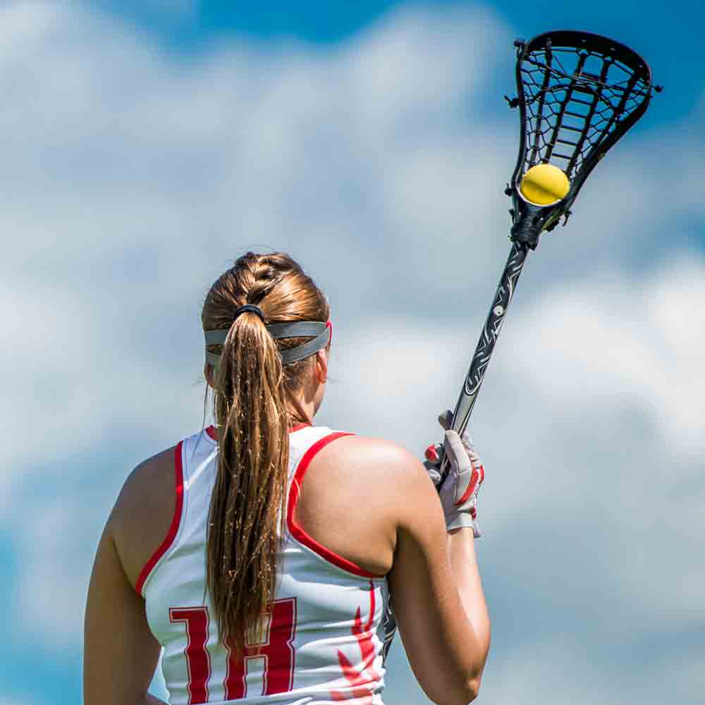 SDSU Women's Lacrosse member holding lacrosse stick with a ball.

