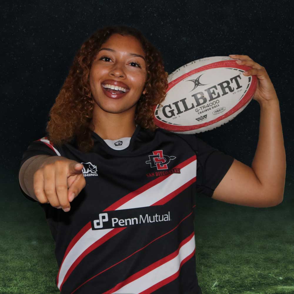 Smiling women's rugby member holding a rugby ball