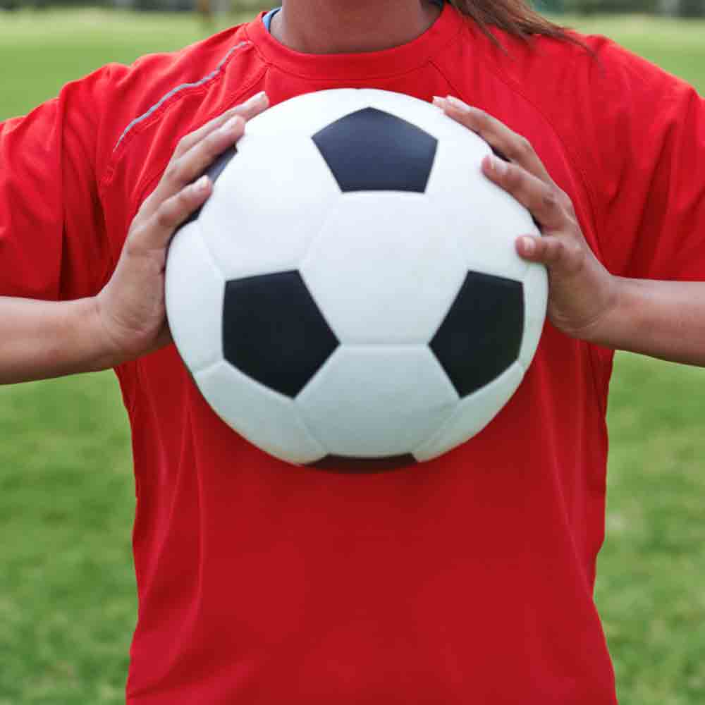 Soccer player holding a soccer ball in front of her chest