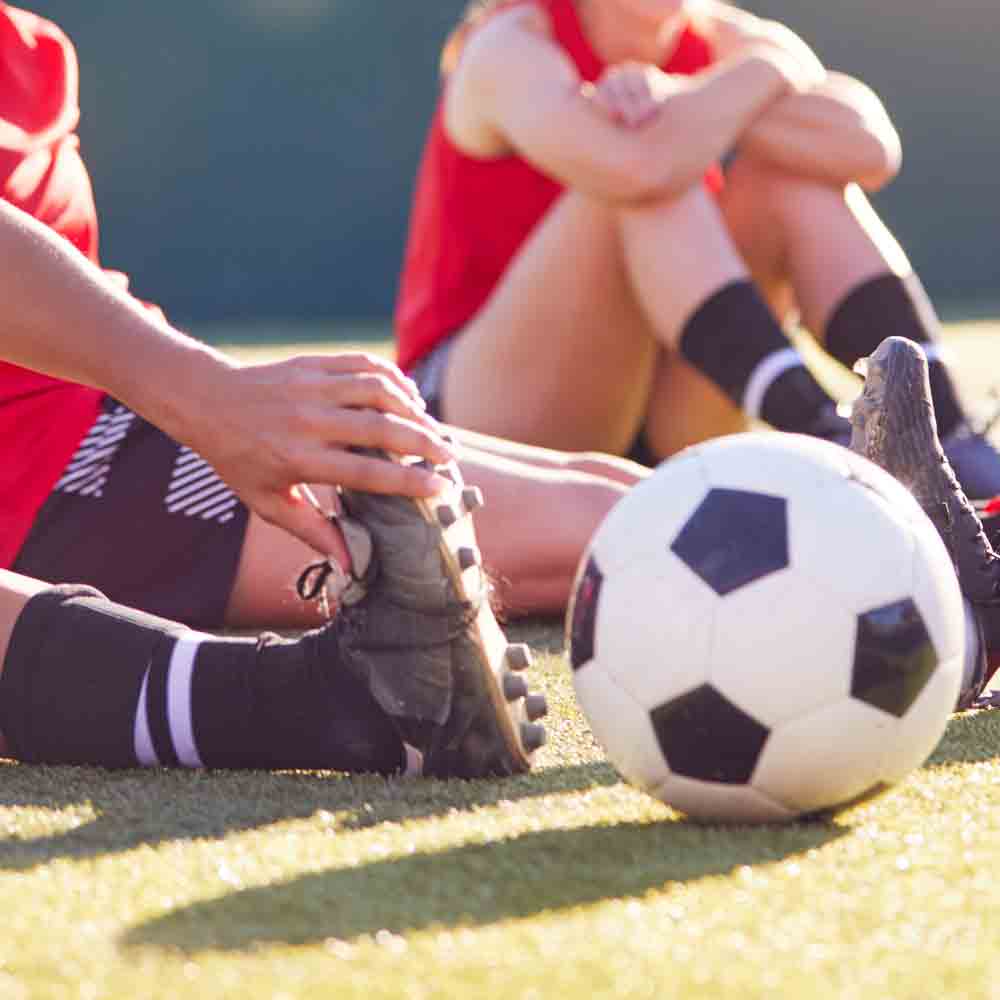 Soccer players sitting on the grass next to a soccer ball