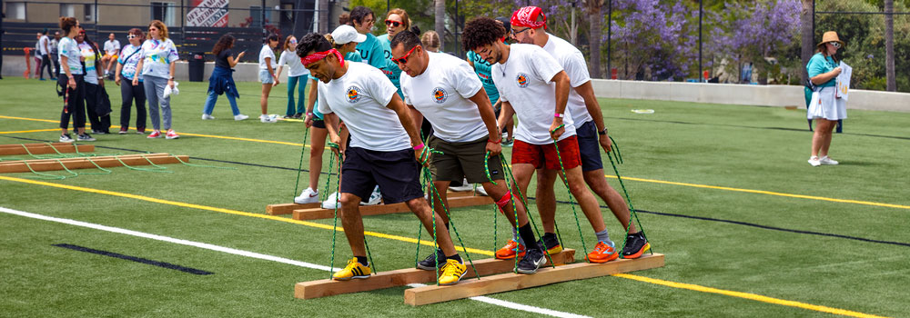 Staff Field Day - team walking on wood planks across grass