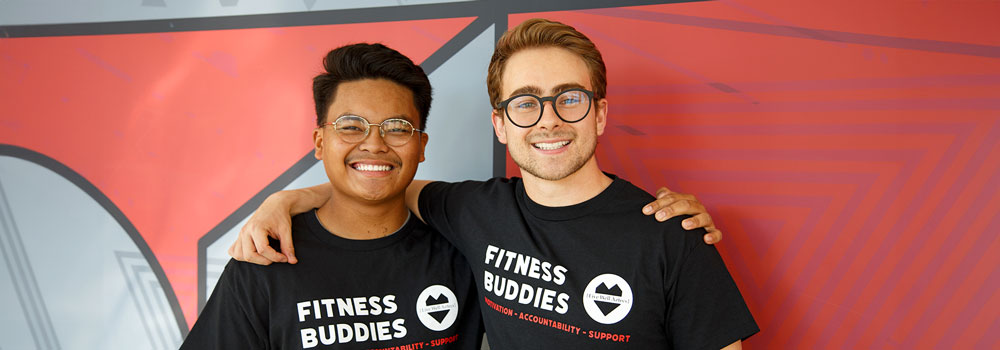 Two smiling students wearing SDSU Fitness Buddies t-shirts
